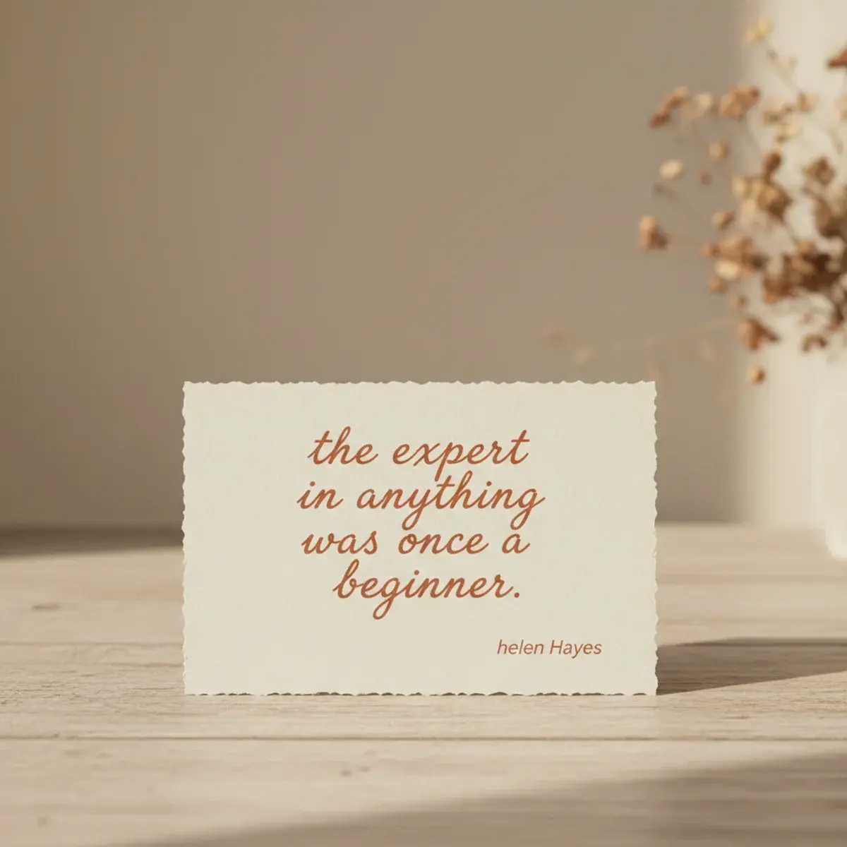 A vintage typewriter on a wooden desk with paper showing a single typed motivational sentence, beside a cup of coffee and dried flowers