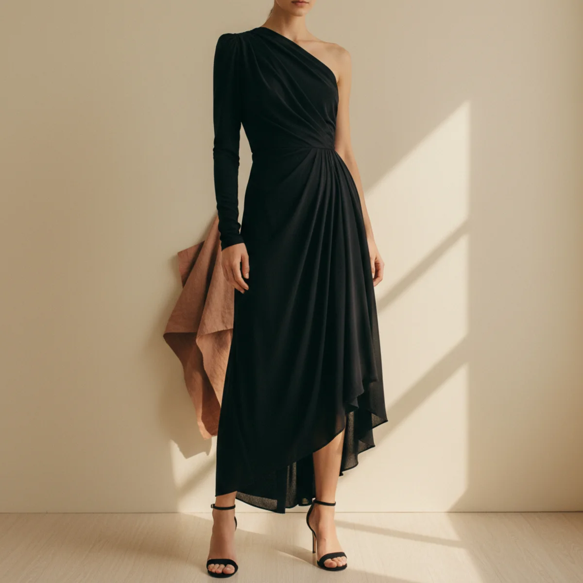 Faceless full-length editorial shot of an asymmetric black midi dress with a one-shoulder neckline and fluid fabric