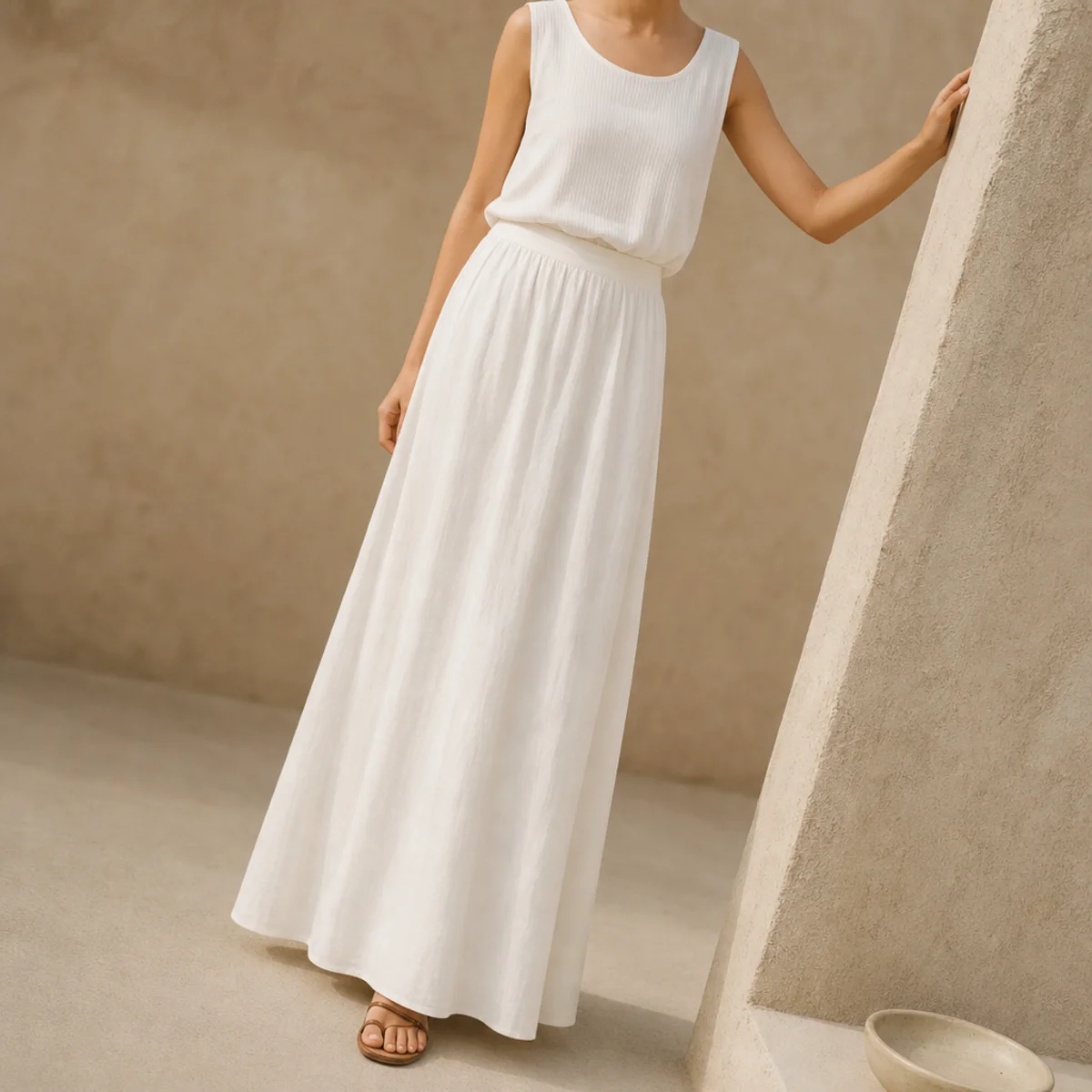 Faceless full-length shot of an all-white outfit with a flowing white maxi skirt and white top