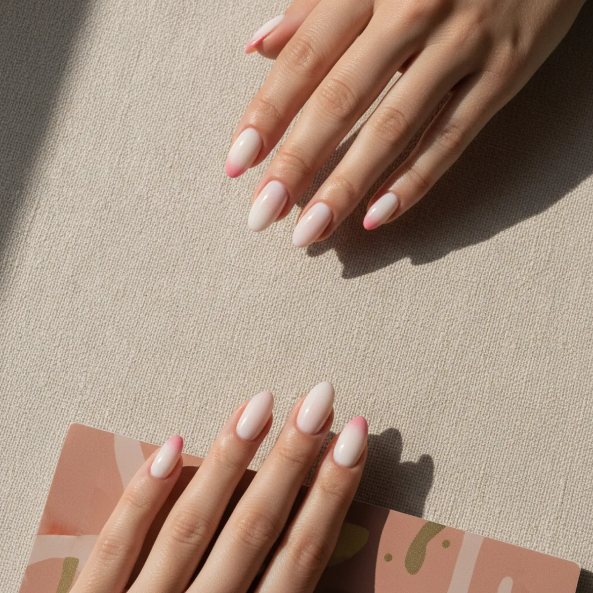 Almond nails with a milky base and soft strawberry-pink tips