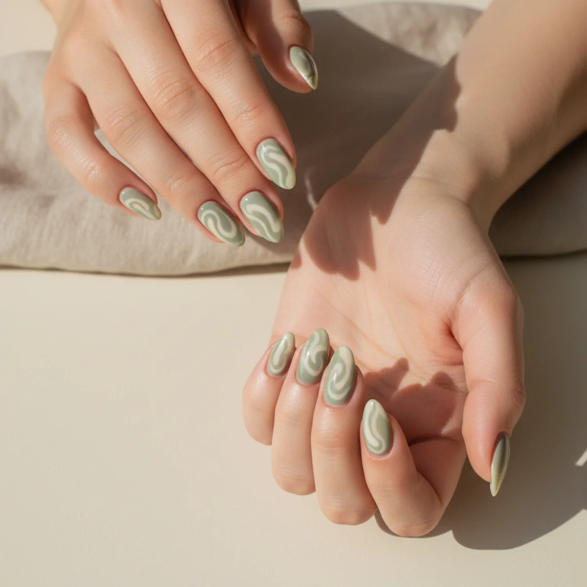 Almond nails with a soft hand-painted swirl of sage green and cream