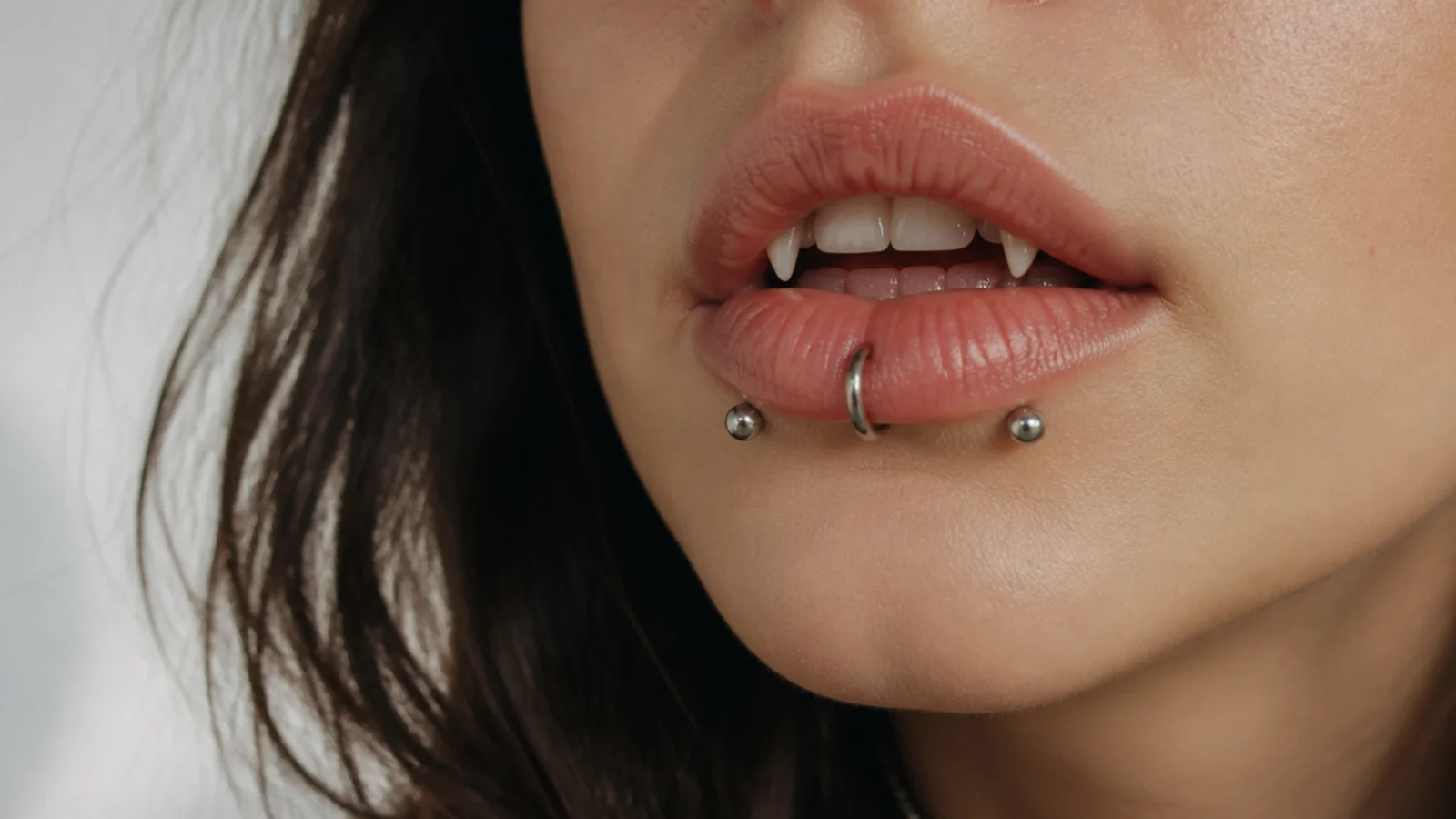 A curated lip look with angel fangs and other piercings