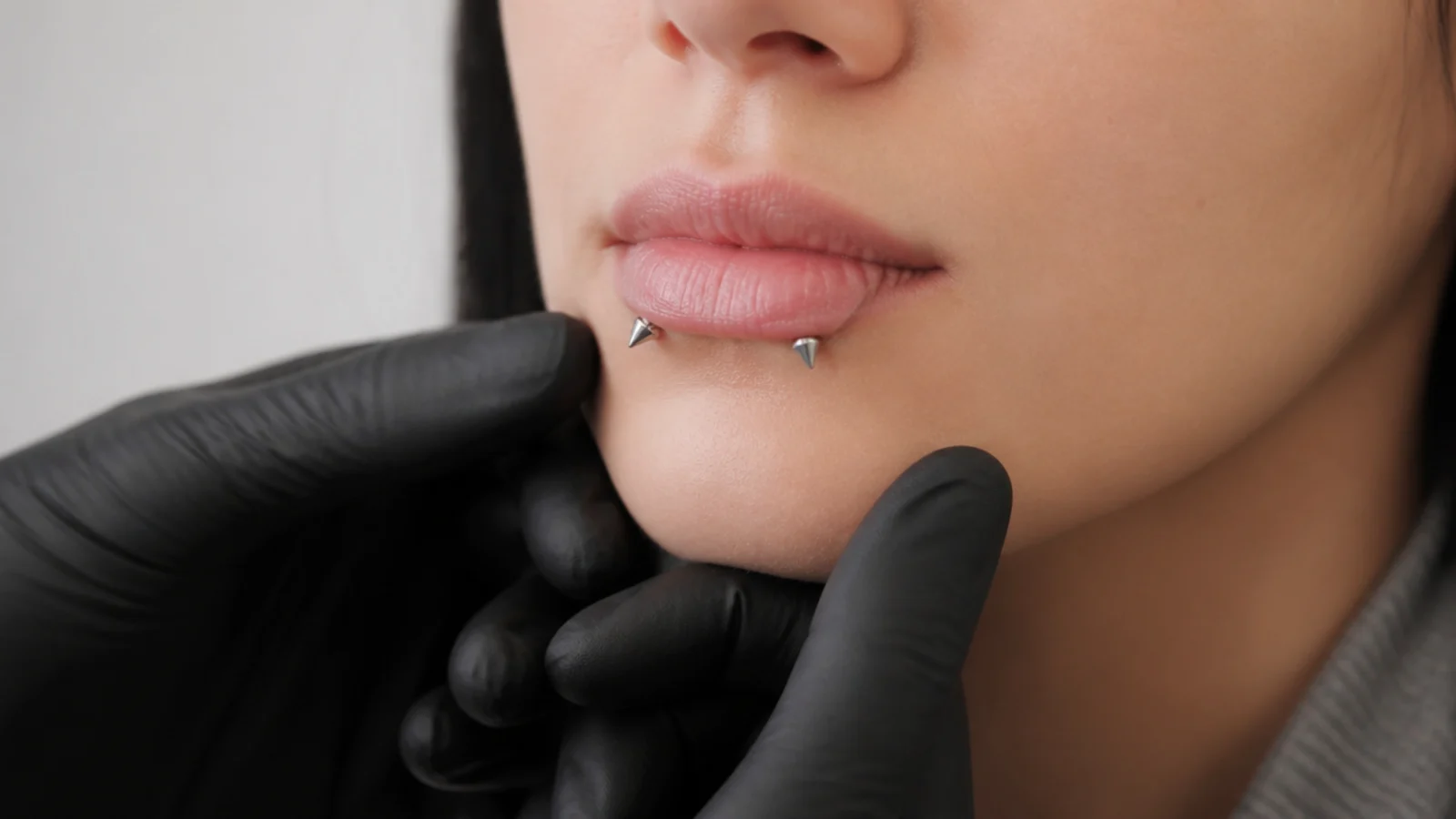 A piercer assessing angel fangs placement on smaller lips