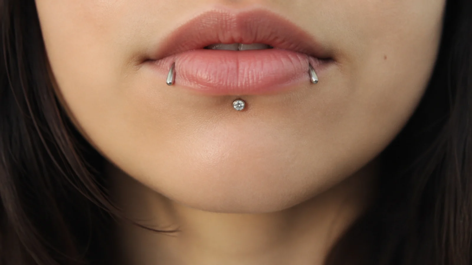 A gem vertical labret with plain angel fangs studs