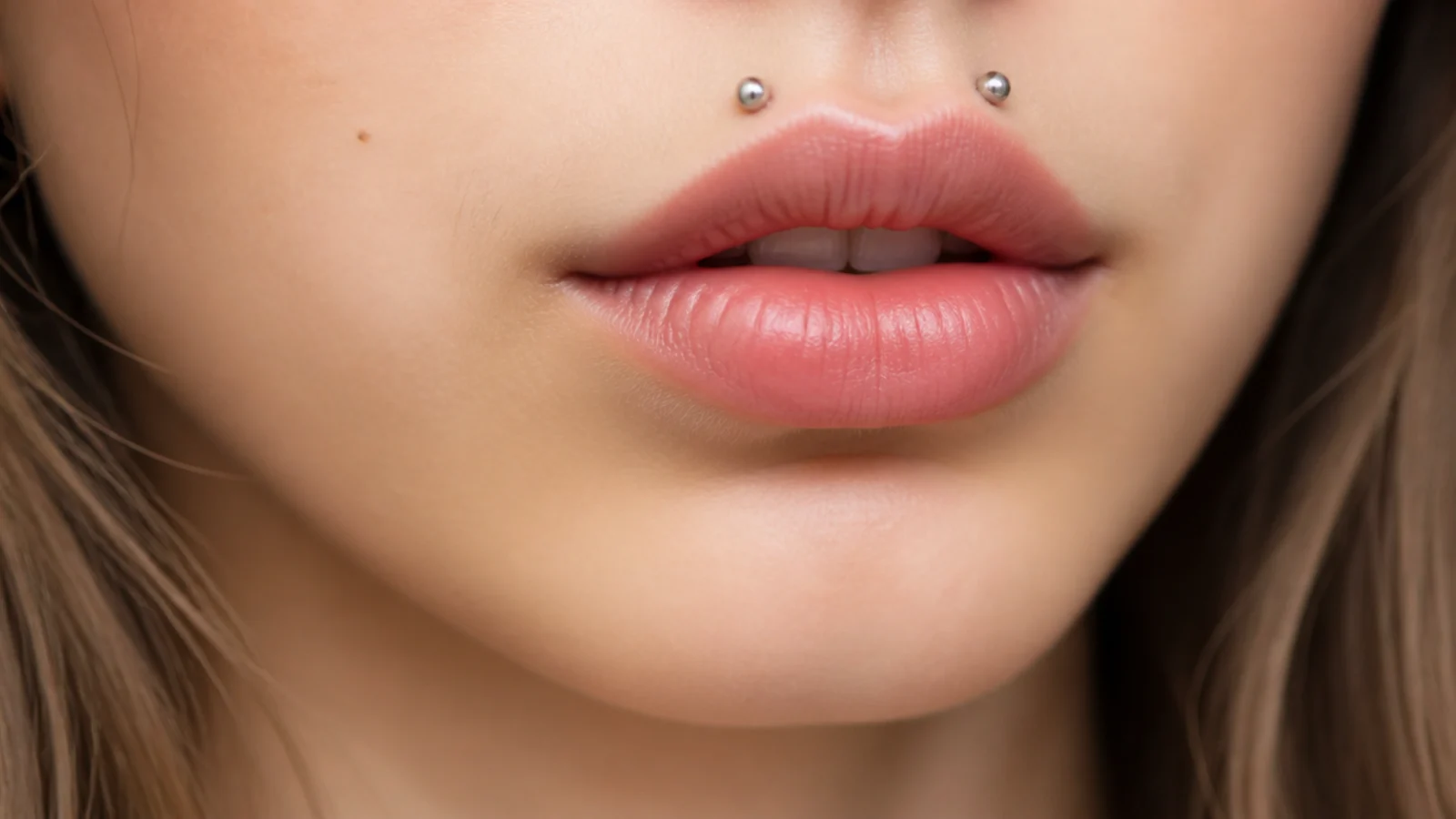 Inverted angel fangs piercings above the upper lip with studs
