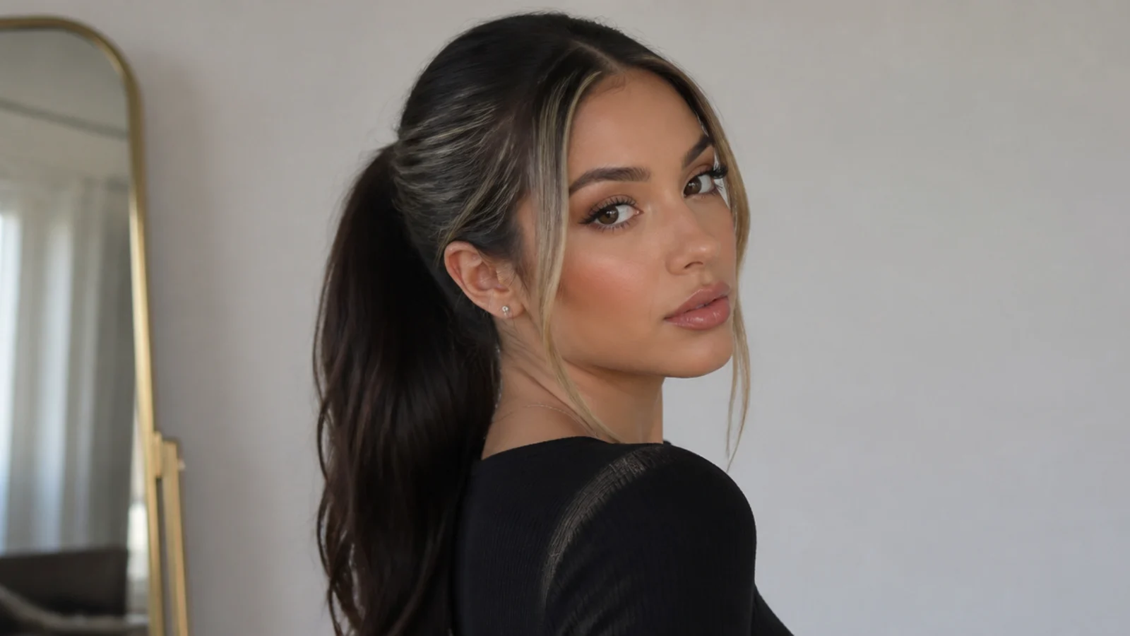 Black hair in a sleek ponytail with money piece pieces framing the face