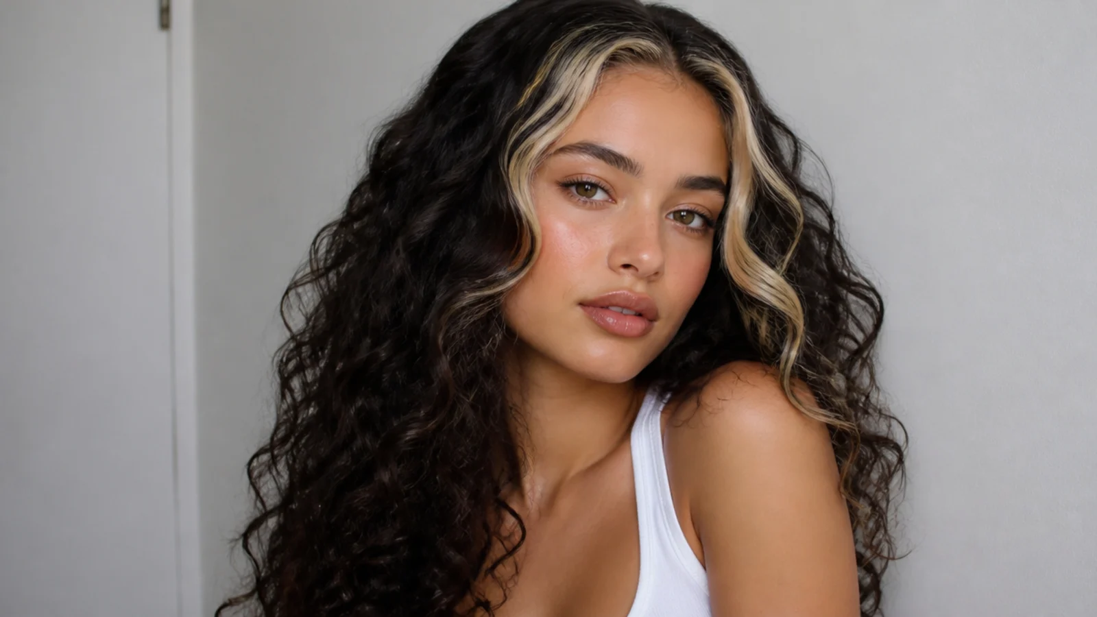 Dark curly hair with a bold blonde money piece statement