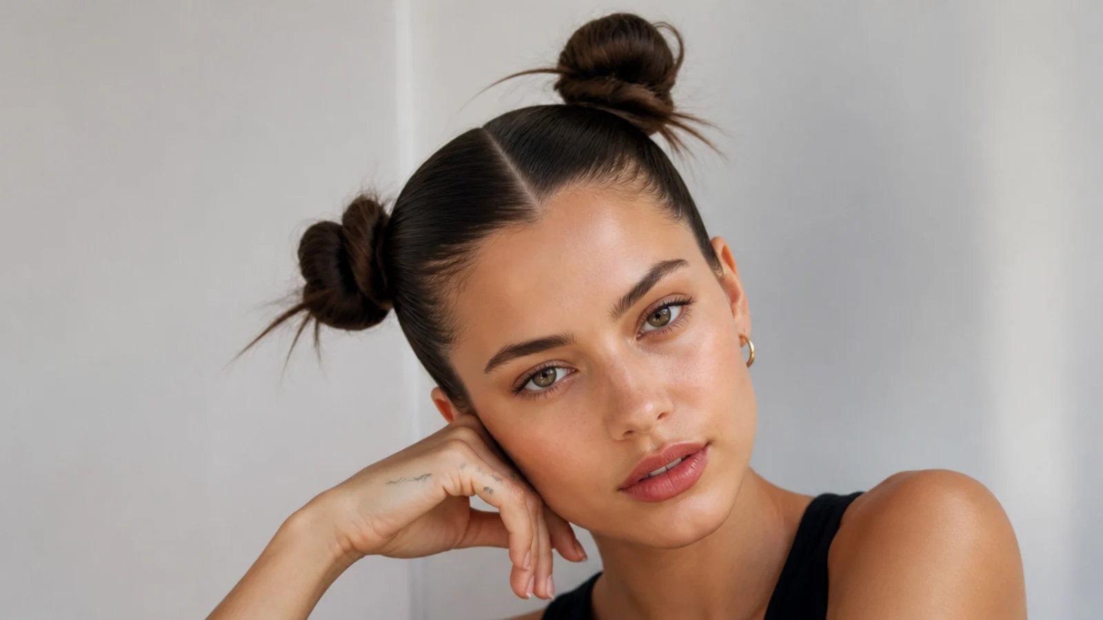 Slicked space buns set asymmetrically for an editorial look