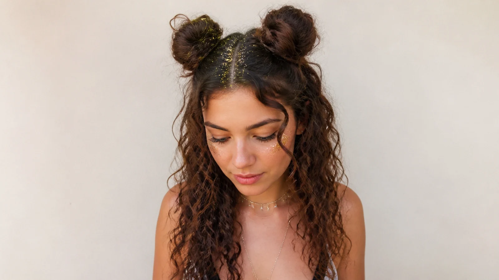 Curly space buns with glitter along the part for a festival