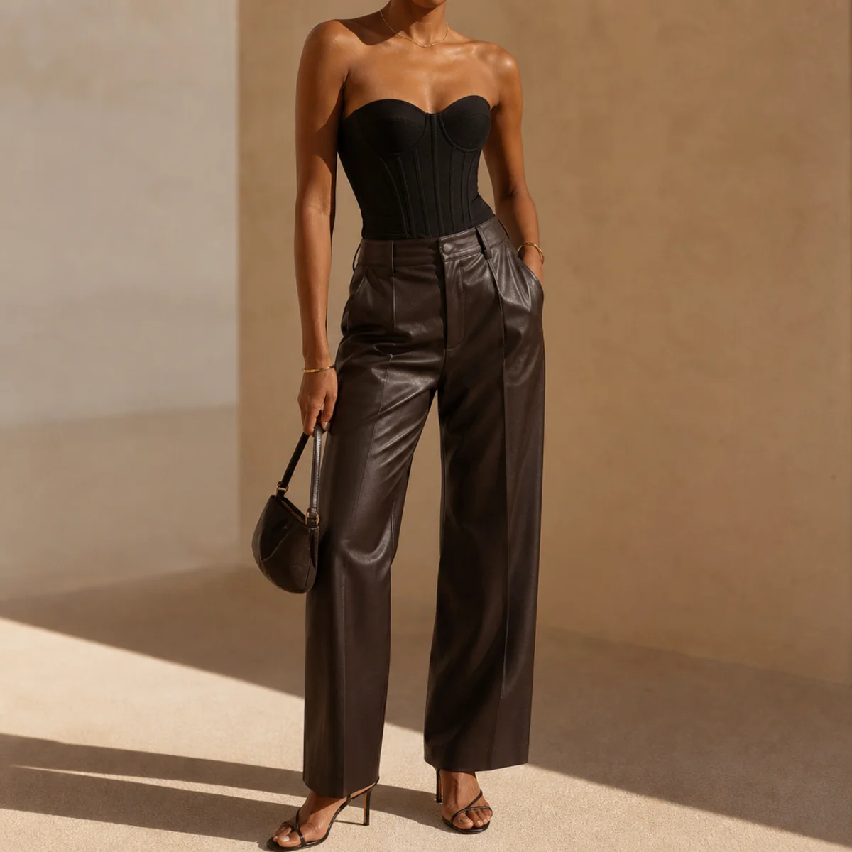 Faceless waist-up editorial shot of a black structured corset top with leather trousers and heels