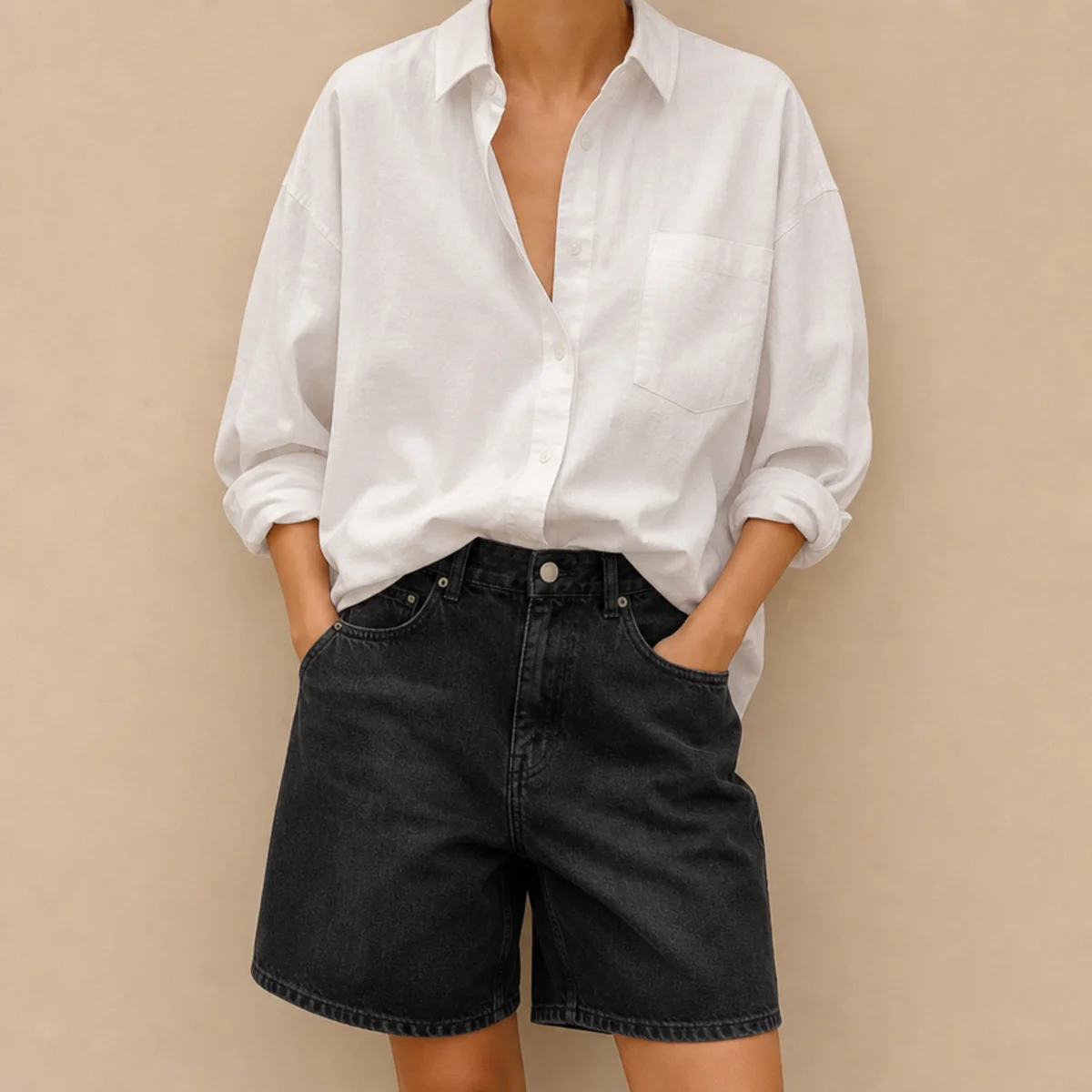 Faceless waist-up shot of an oversized white shirt half-tucked into black denim jorts