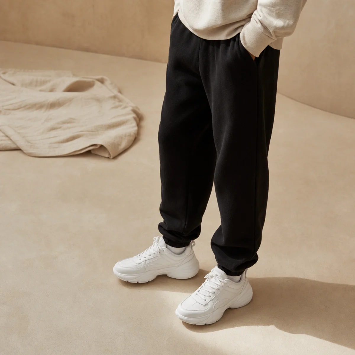Faceless waist-down shot of black sweatpants with bright white chunky sneakers