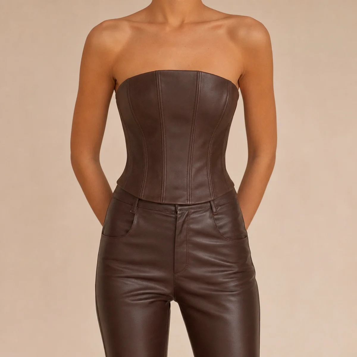Faceless waist-up shot of a structured corset top with slim leather trousers