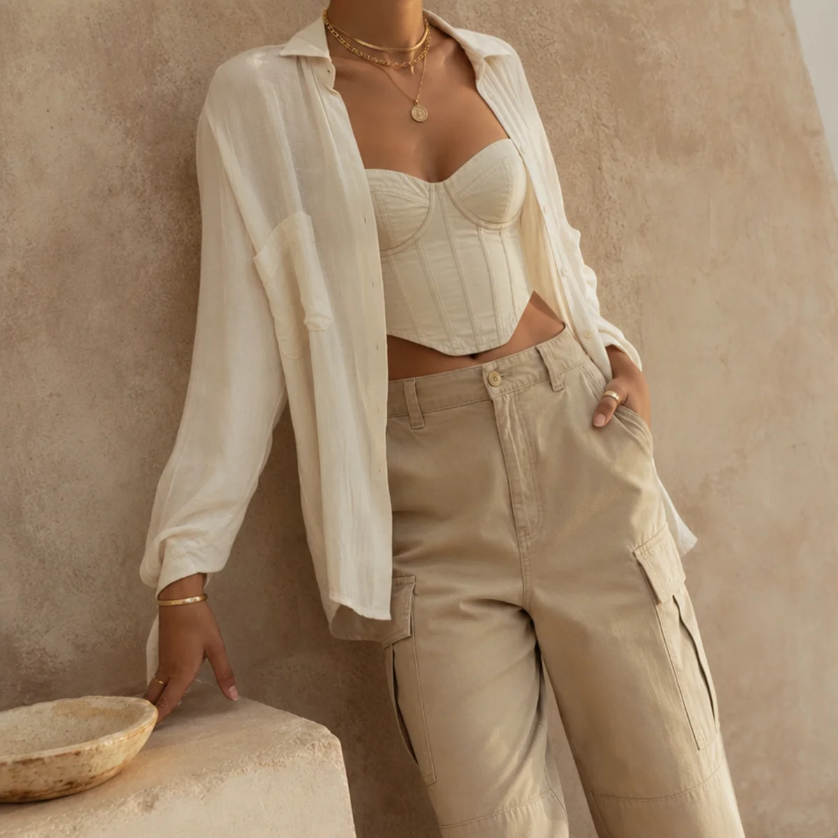 Faceless waist-up shot of a corset top under an open shirt with cargo pants