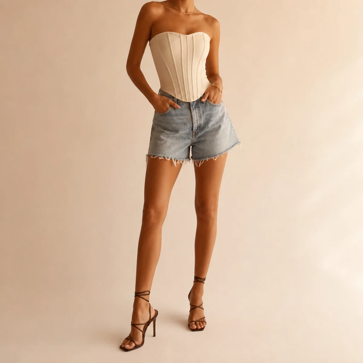 Faceless waist-up shot of a structured corset top with denim jorts and strappy heels