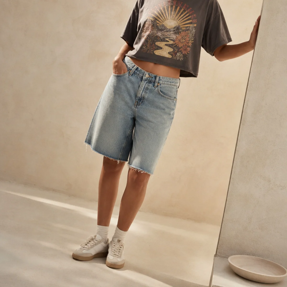 Faceless waist-down shot of denim jorts with a cropped graphic tee and sneakers for an everyday look