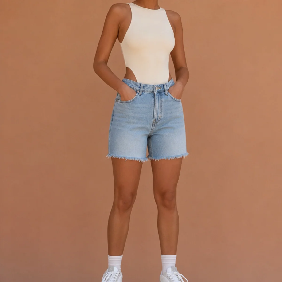 Faceless waist-up shot of a fitted bodysuit with denim jorts and sneakers for an everyday look