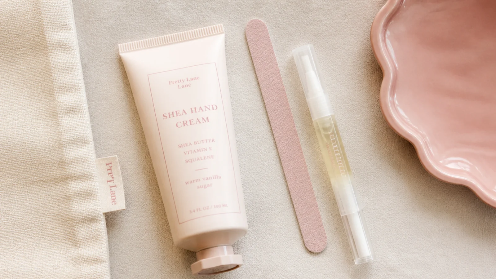 Faceless flat-lay of a tube of shea hand cream beside a small nail file and cuticle oil