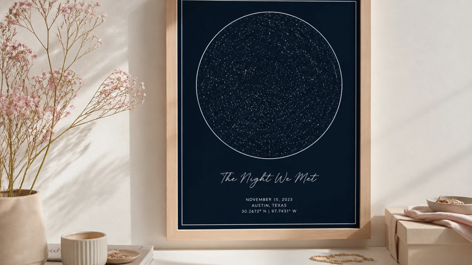 Faceless shot of a framed dark-navy star map print hanging on a pale wall