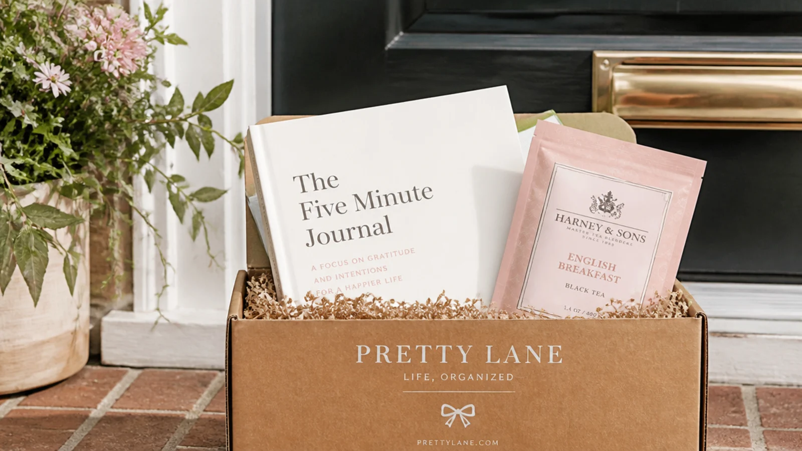 Faceless shot of a kraft subscription box on a doorstep with a book and tea peeking out