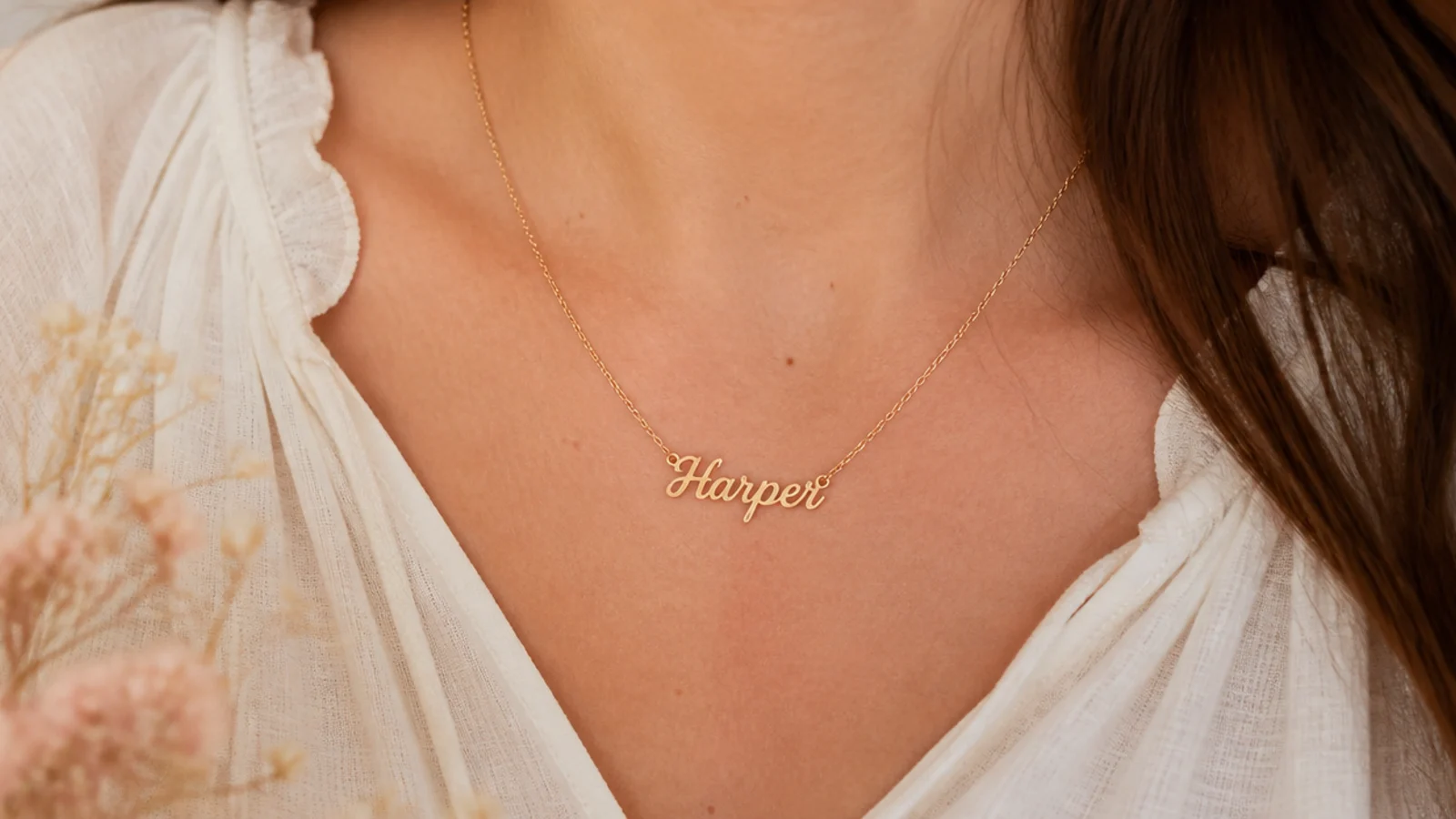 Faceless close-up of a fine gold nameplate necklace resting at the collarbone