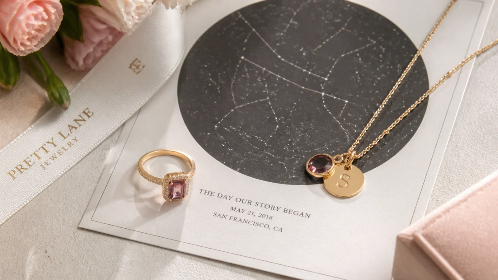 Faceless flat-lay of a birthstone ring, star map print and gold necklace arranged together