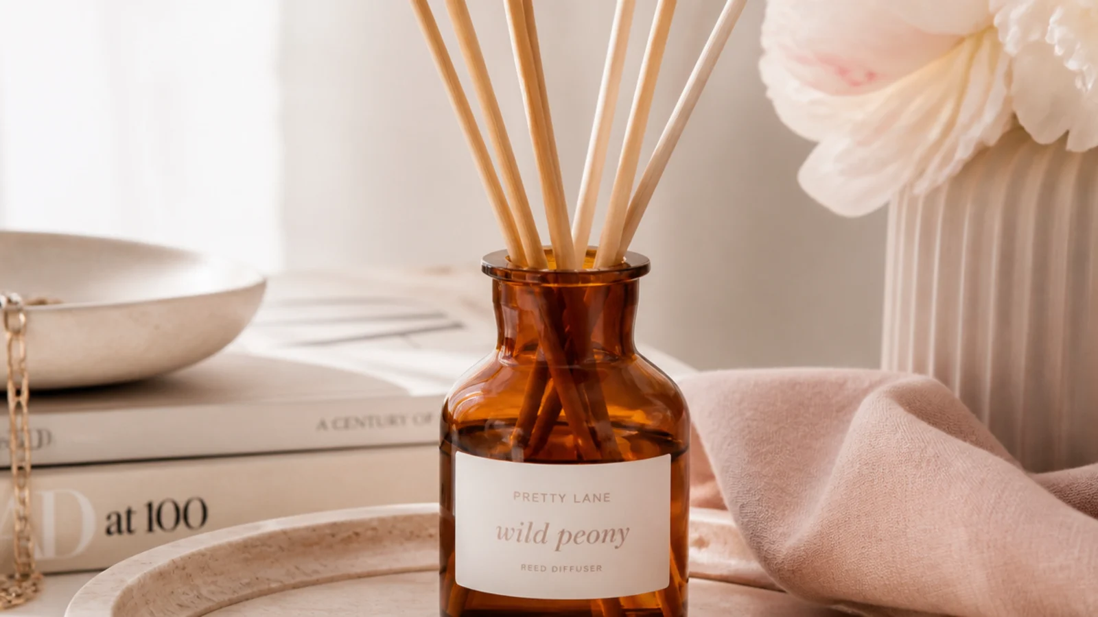 Faceless close-up of an amber glass reed diffuser with natural rattan reeds