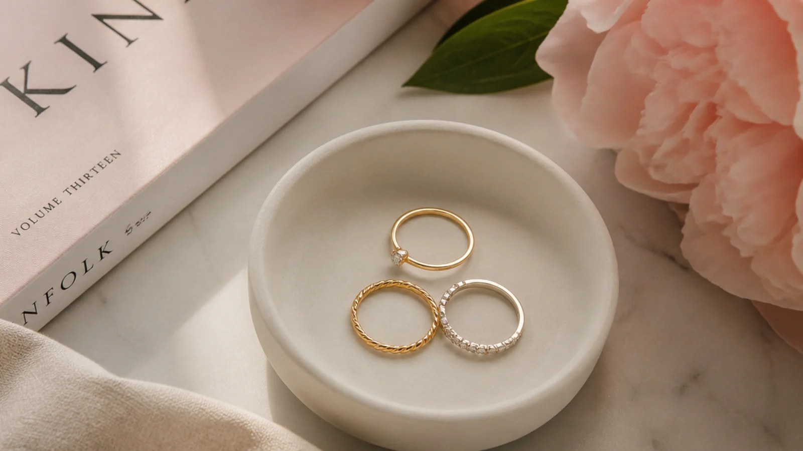 Faceless flat-lay of a small matte ceramic ring dish holding delicate rings