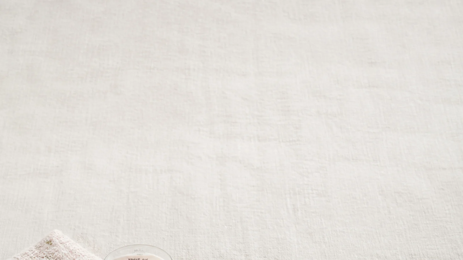 Faceless flat-lay of budget gifts for her under $25 arranged on a neutral linen surface