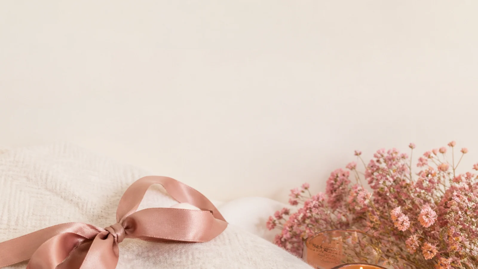 Faceless flat-lay of a folded cream throw blanket, a lit amber candle and wool socks with the title cozy winter gift ideas for her