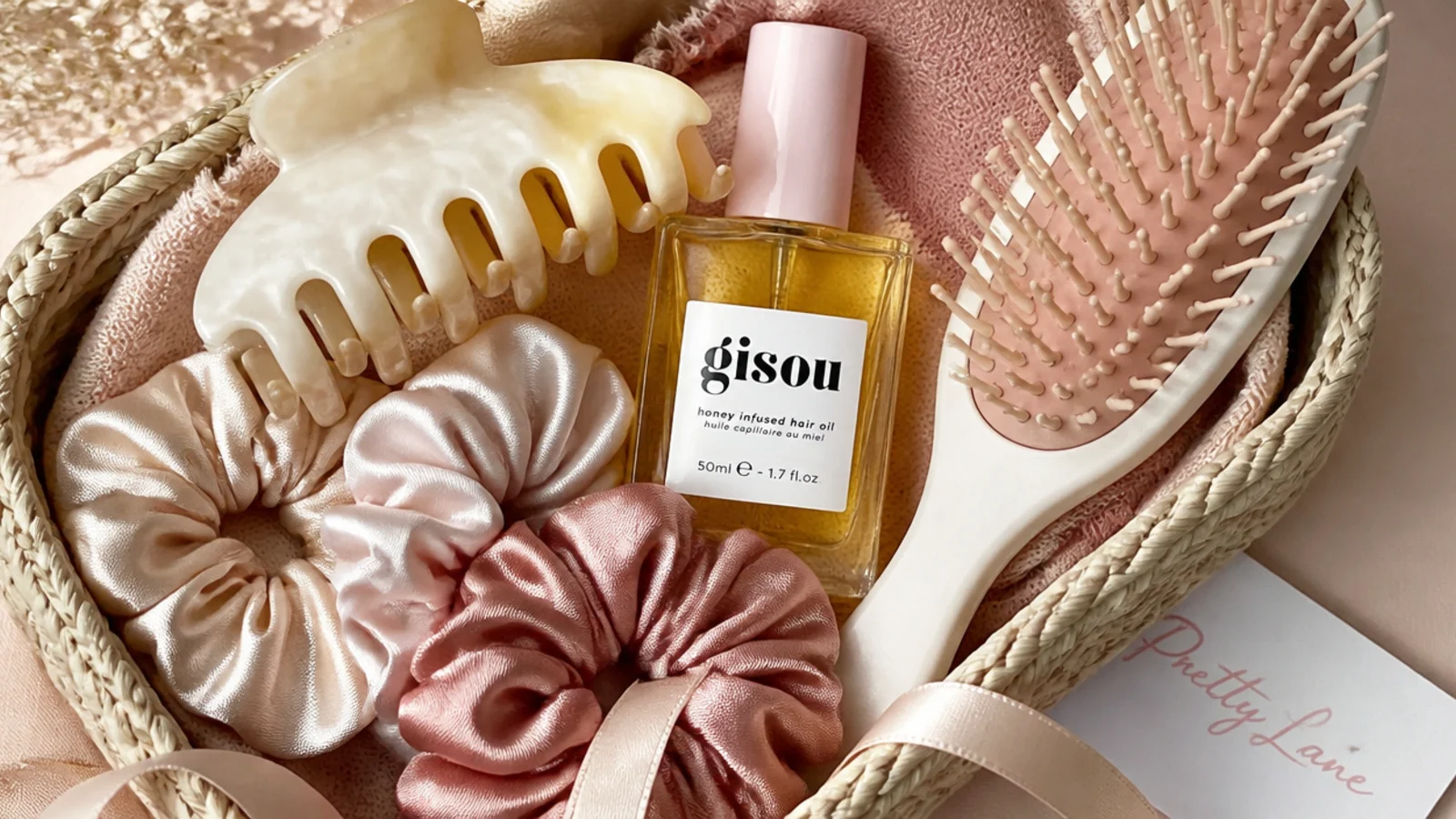 Faceless flat-lay of a hair care basket with silk scrunchies, a claw clip, hair oil and a brush