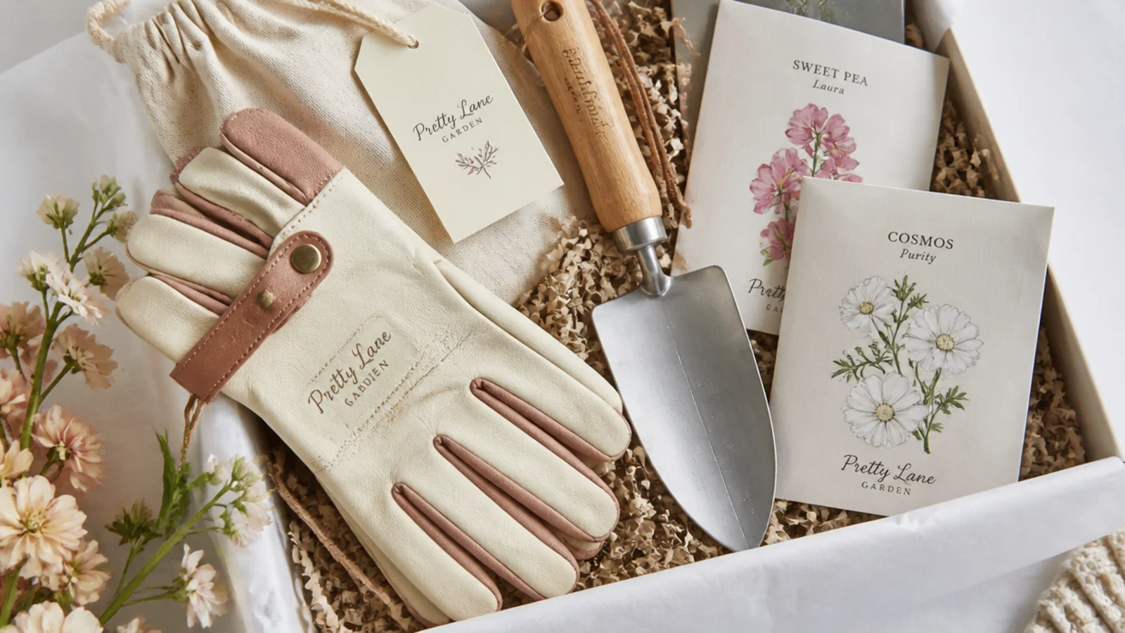 Faceless overhead shot of a gardening gift hamper with leather-palm gloves, hand trowel and seed packets