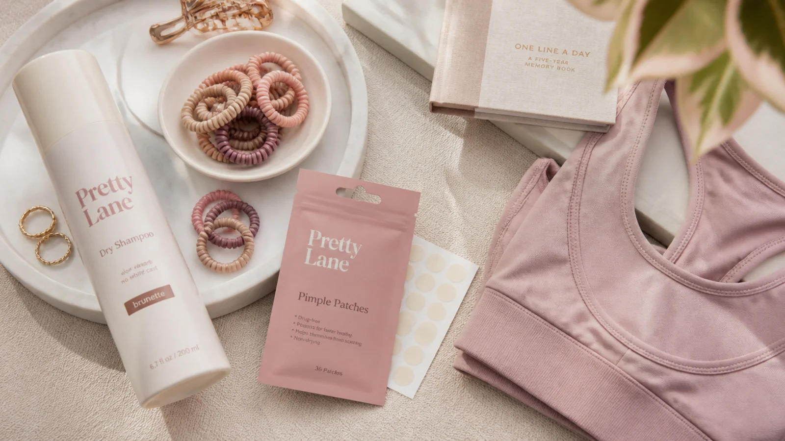 Faceless flat lay of dry shampoo, no-crease hair ties, pimple patches and a folded sports bra