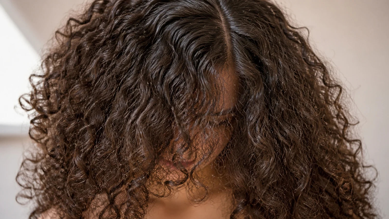 Big volume frizzy curly hair with a center part and wide halo framing both sides of the face