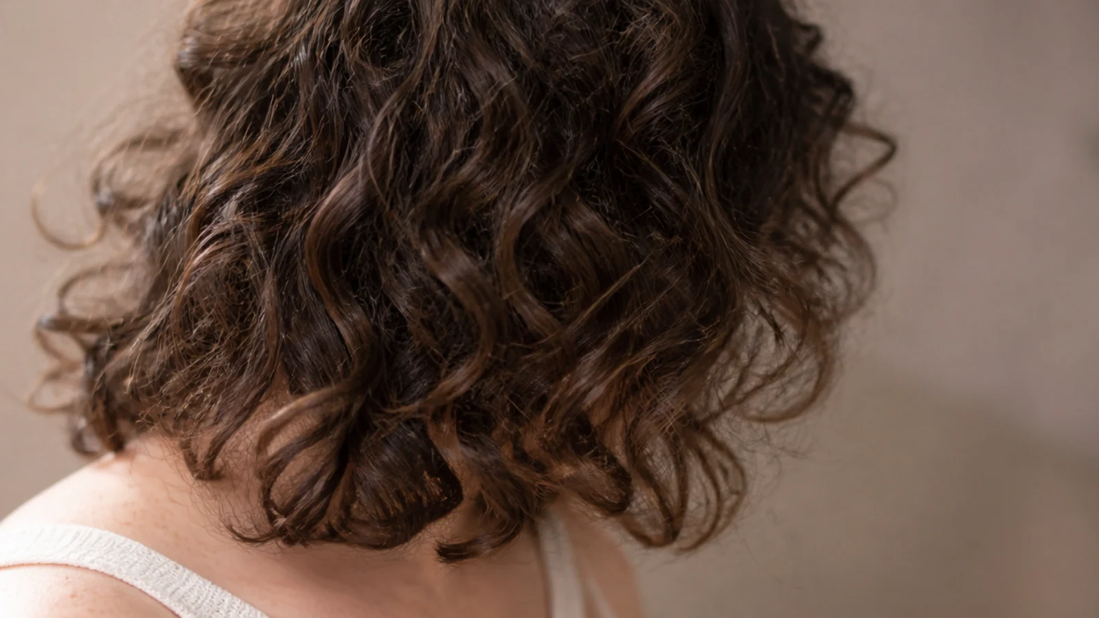 Frizzy curly hair cut to collarbone length with long face framing layers and internal debulking