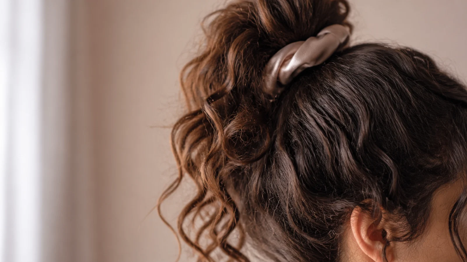High loose pineapple ponytail on second day frizzy curly hair secured with a satin scrunchie
