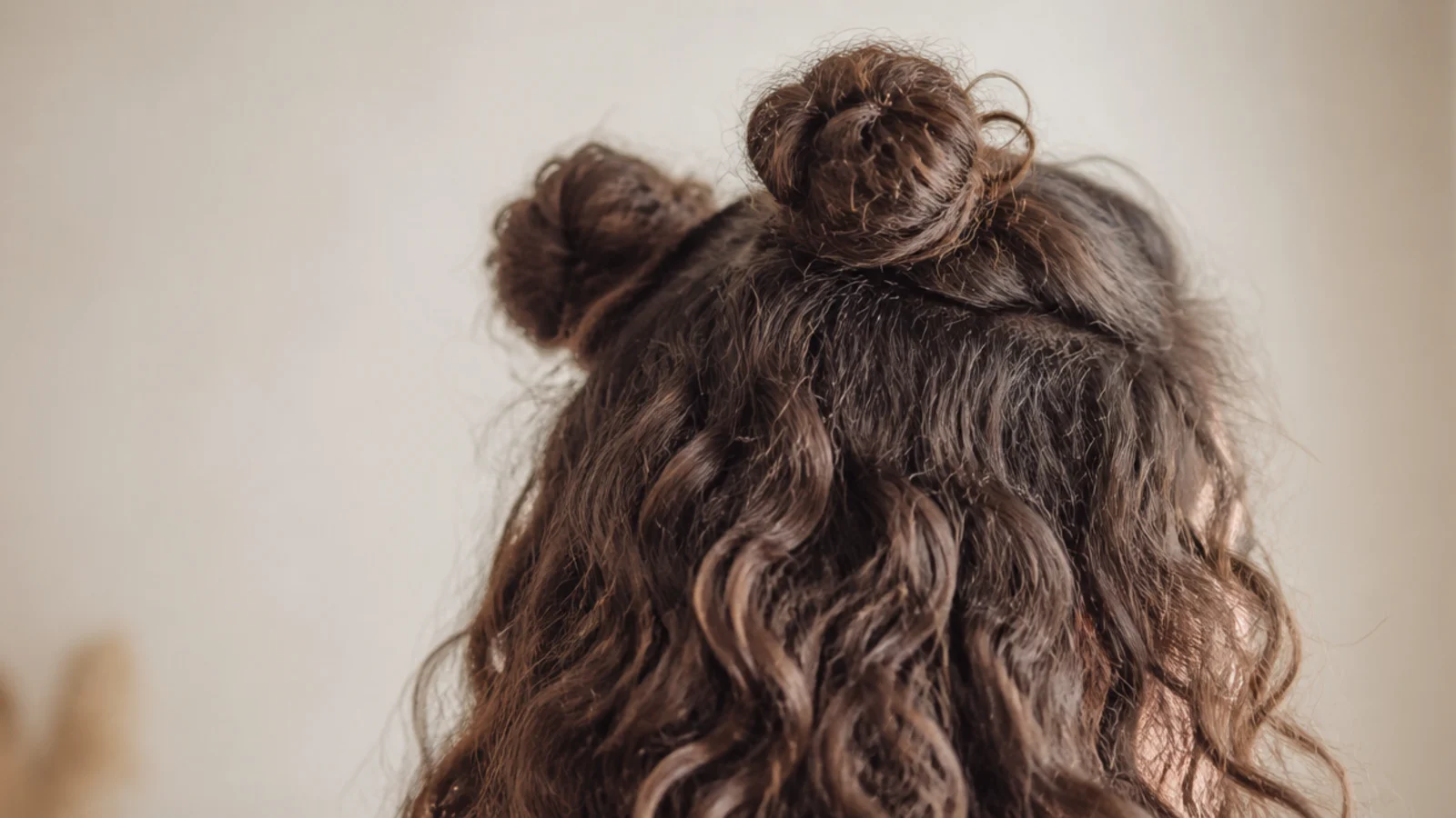 Half up space buns on frizzy curly hair with two small buns at the crown and texture left loose below
