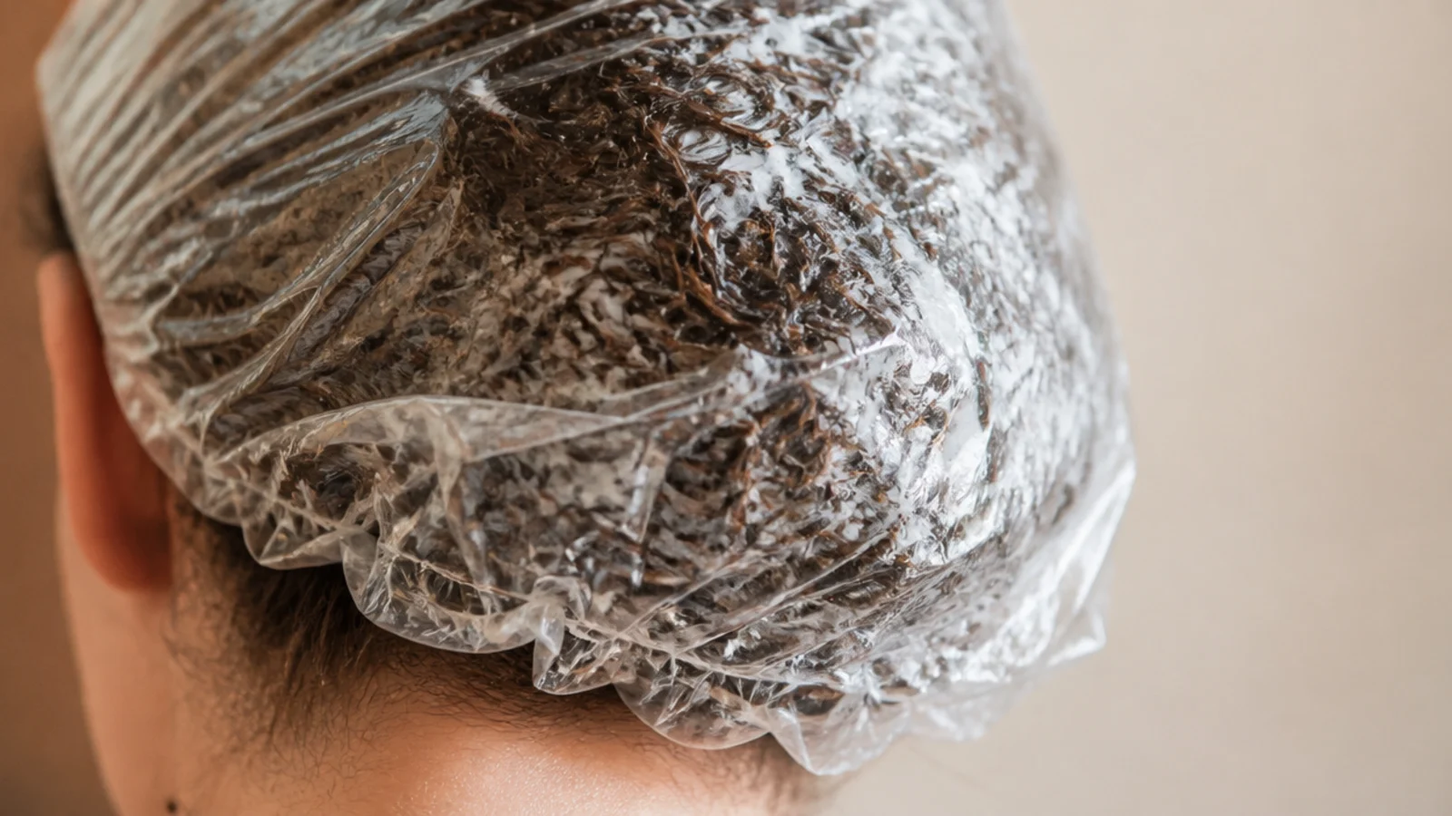 Deep conditioning mask under a shower cap using body heat to treat frizzy dry hair