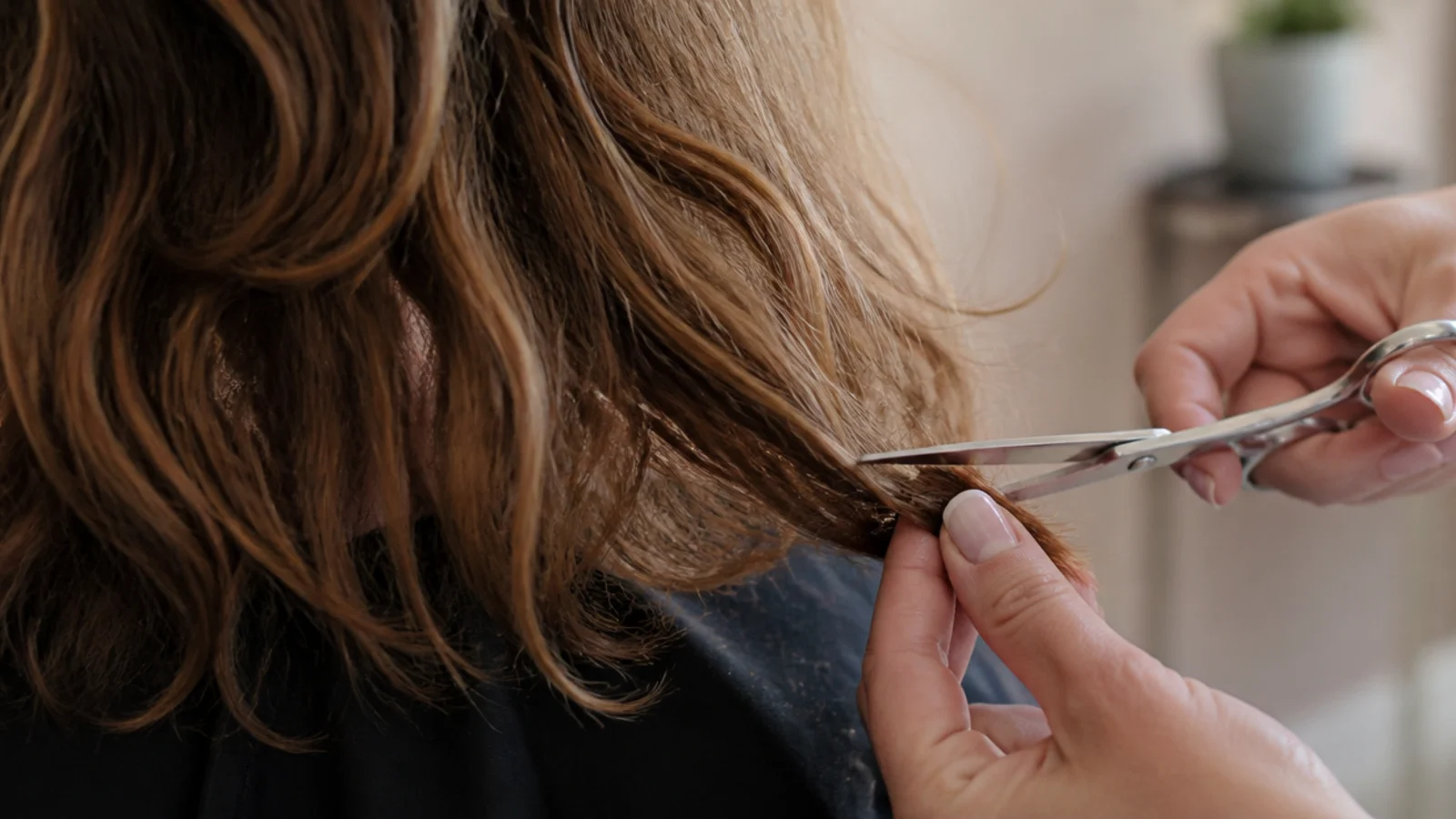 Stylist point cutting the ends of frizzy hair at a trim instead of using thinning shears