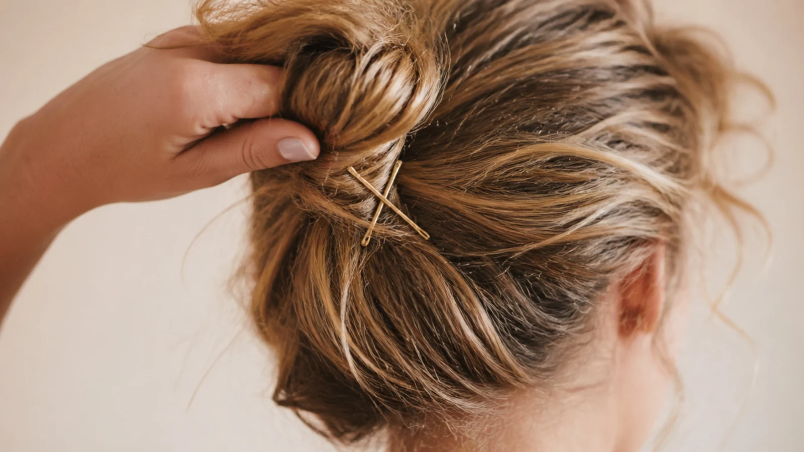 Loose messy bun on frizzy hair gathered with fingers and secured with two crossed bobby pins