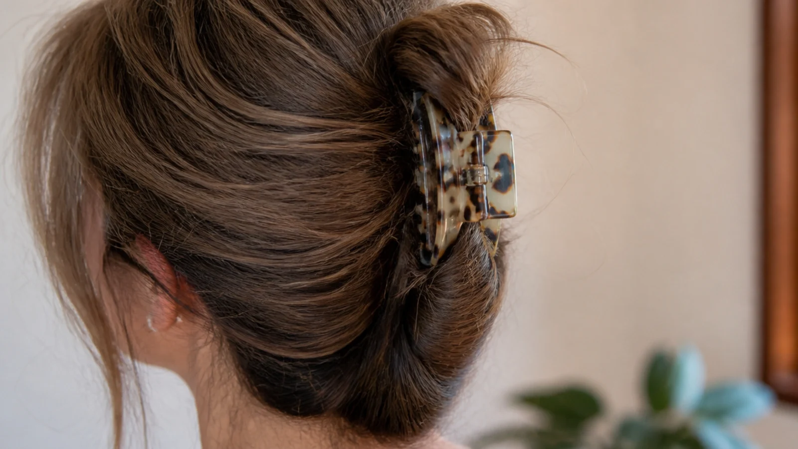 Frizzy mid-length hair twisted into a vertical French twist and secured with a large claw clip