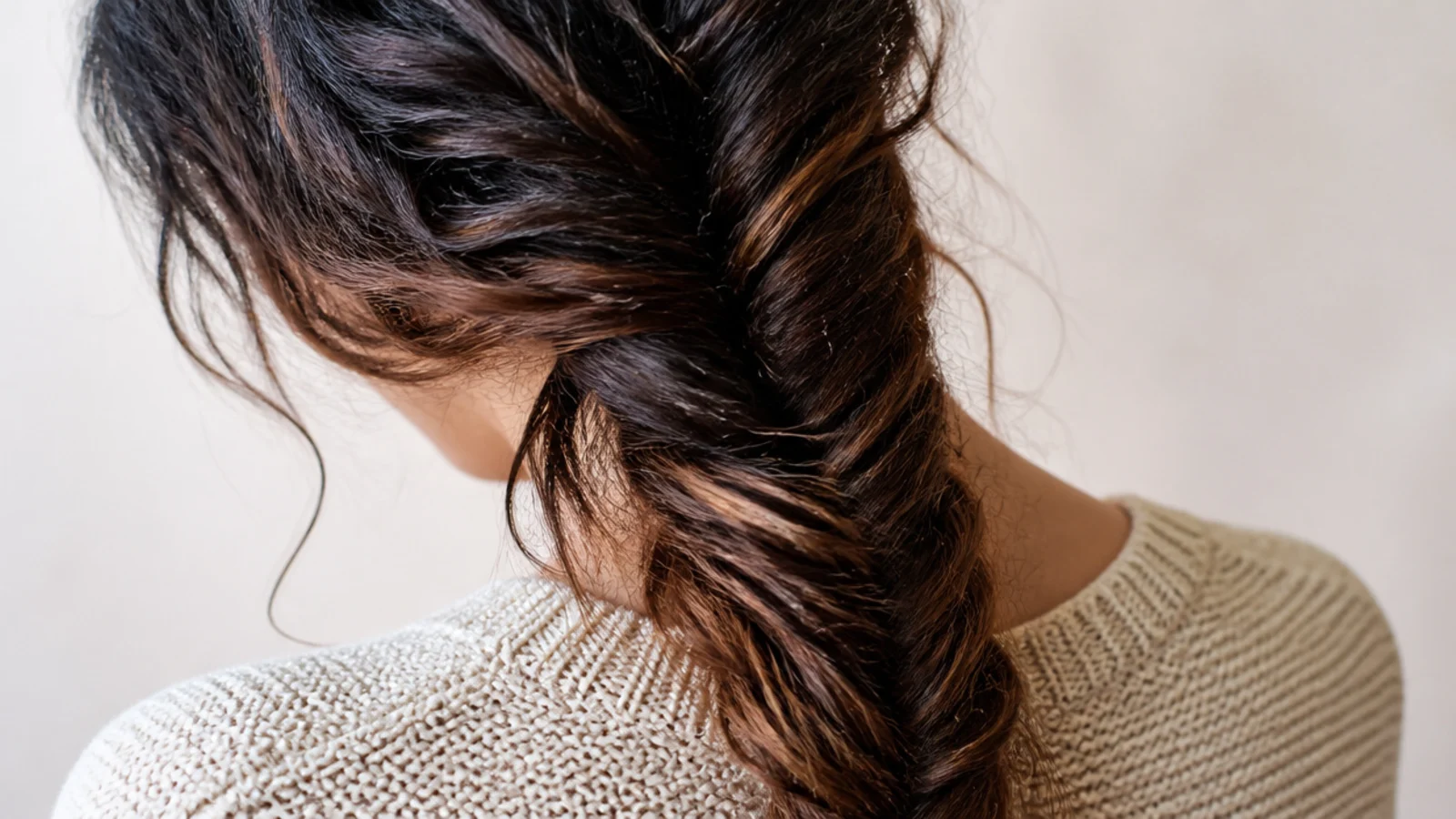 Loose side fishtail braid on long frizzy high porosity hair draped over one shoulder