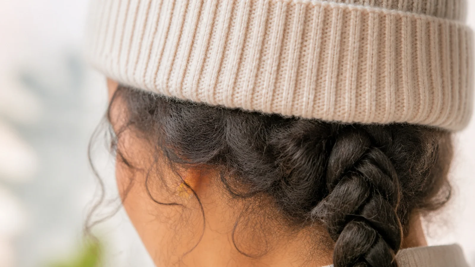 Ribbed beanie worn over frizzy hair with the lengths braided and tucked to prevent friction frizz