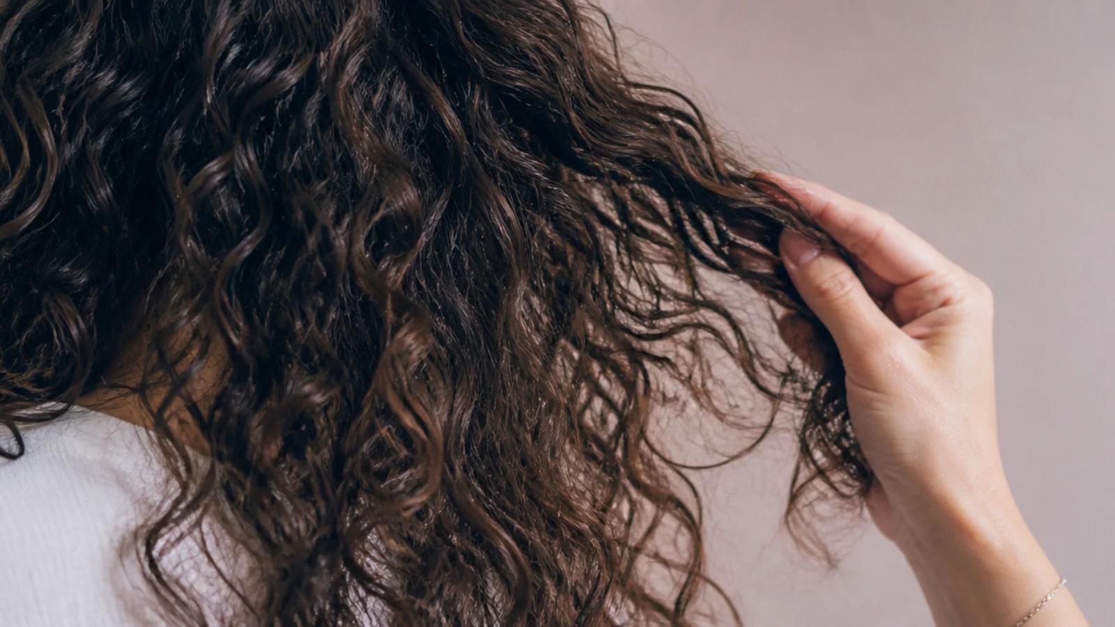 Curly frizzy hair separated with fingers instead of a brush to keep the curl clumps intact