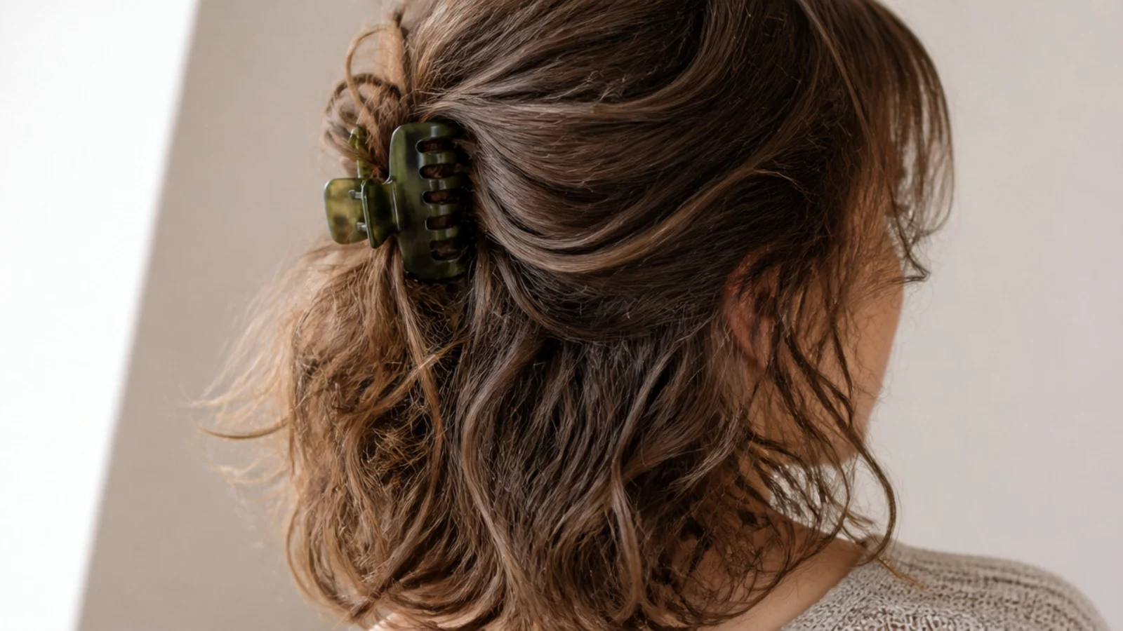 Half-up claw clip twist on shoulder length frizzy hair with the lower half left textured and loose