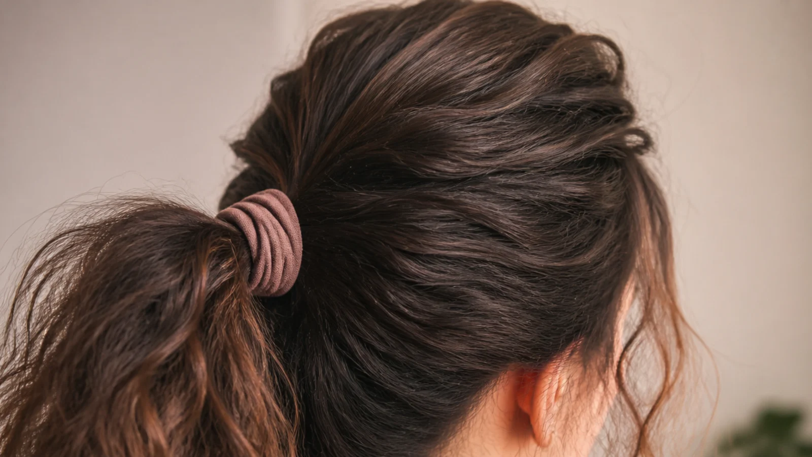 Bouffant ponytail with lifted crown volume on medium length frizzy hair tied with a fabric elastic