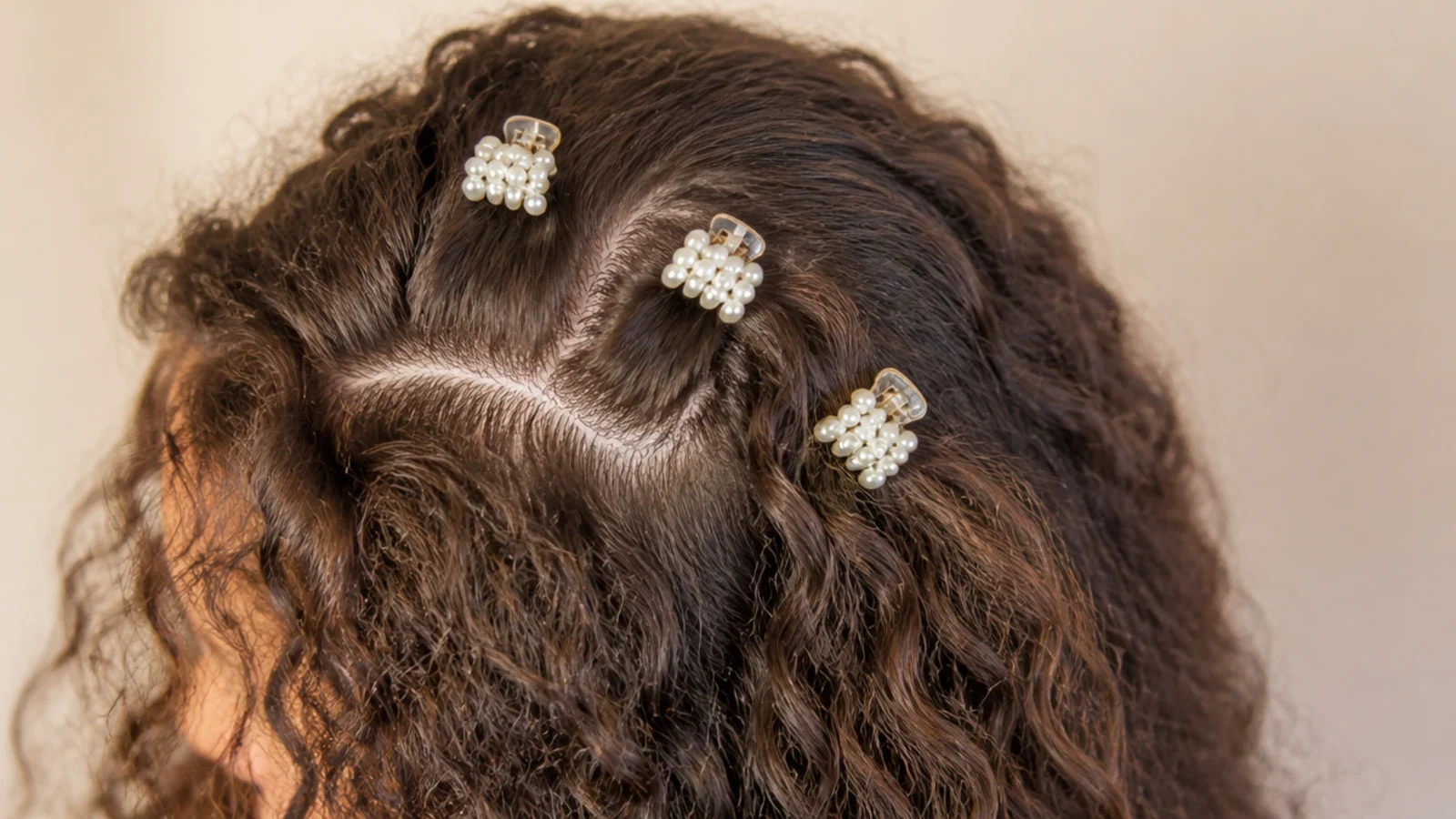 Deep side part on frizzy hair with three mini pearl claw clips arranged in a row along the crown