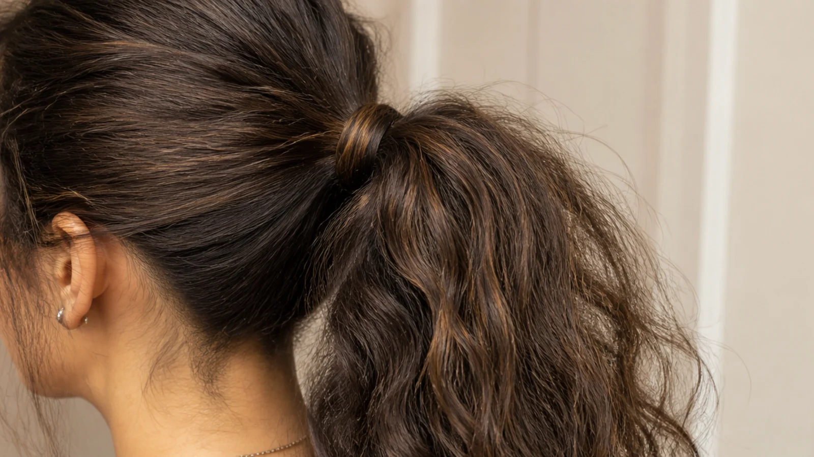 High ponytail on puffy frizzy hair with a half inch strand wrapped around the base to hide the elastic