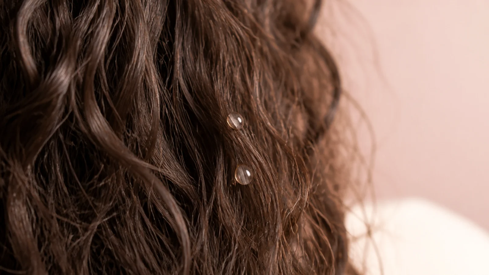 Two drops of silicone anti frizz serum smoothed over the surface of dry frizzy hair