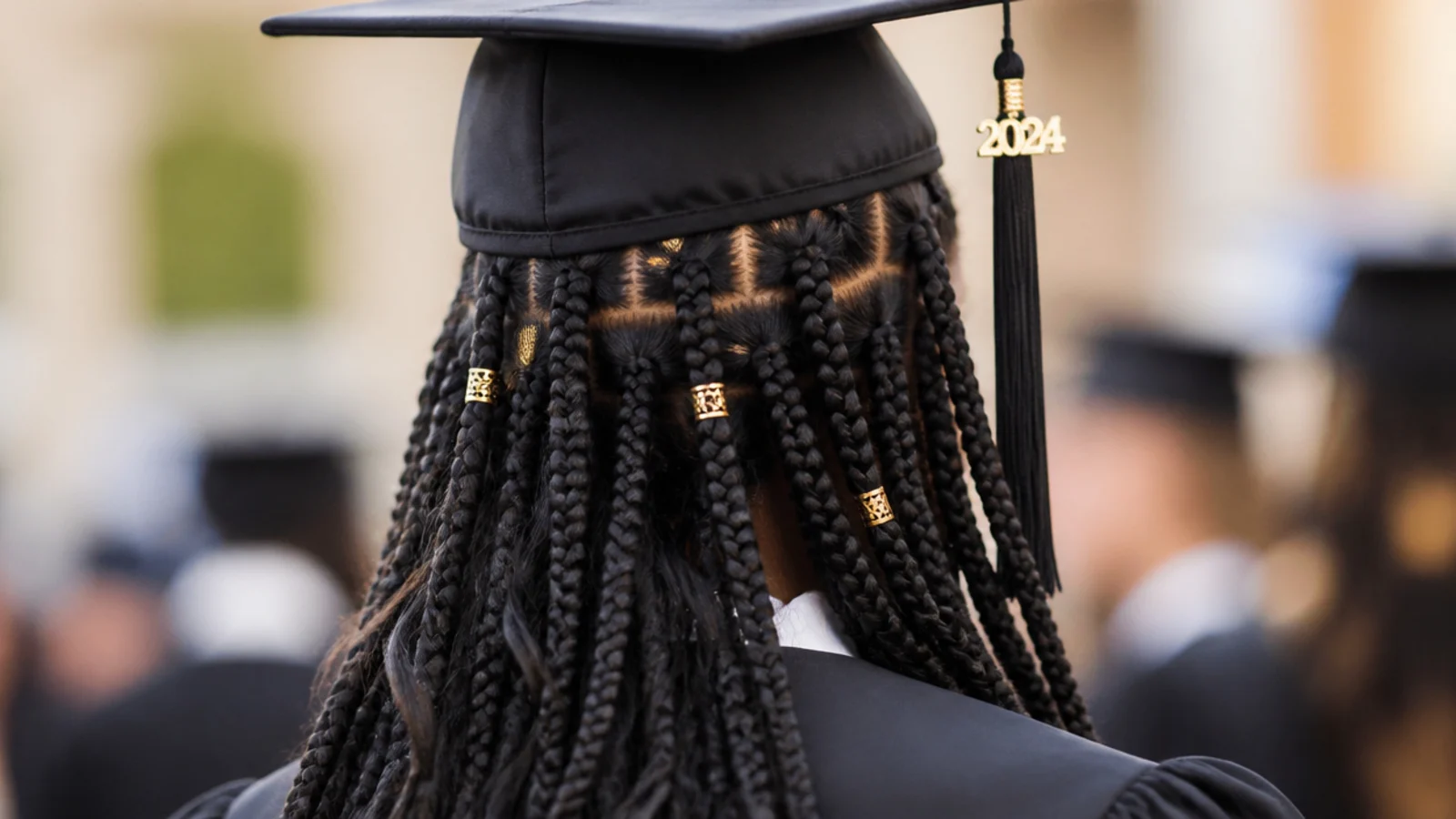 Fulani braids with a center part as a braided graduation hairstyle with cuffs sitting below the cap band